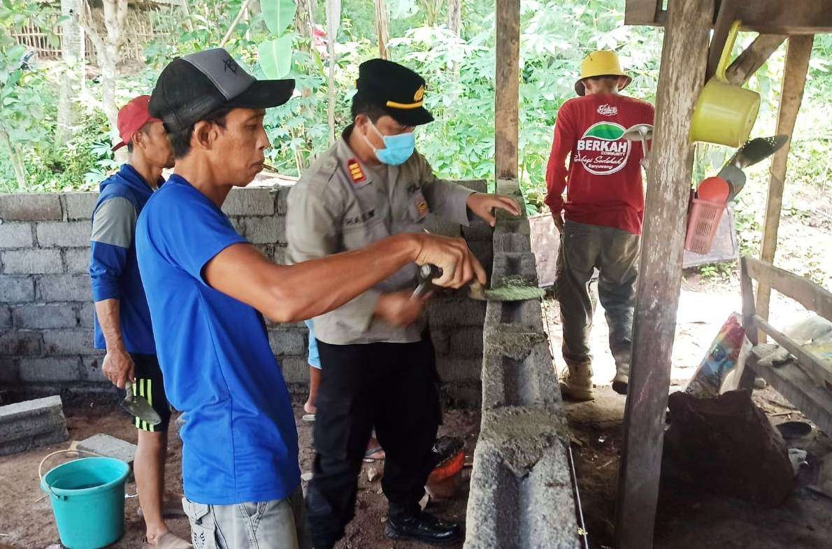 Kapolsek Kalipuro, AKP Hadi Waluyo bersama warga dan anggota komunitas Berkah memasang batako untuk dinding rumah Niriam (foto: Muh Hujaini/Ngopibareng.id)