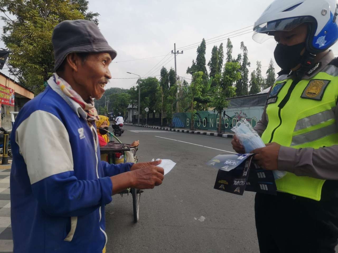 Salah seorang anggota Kamsel Satlantas Polres Bojonegoro membagikan masker gratis warga yang tak pakai kain penutup hidung dan mulut ini, di Bundaran Tugu Adipura Kota Bojonegoro,Selasa 15 Maret 2022.(Foto: Humas Polres Bojonegoro/ngopibareng.id)