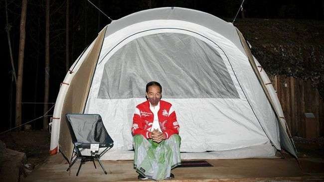 Presiden Jokowi duduk di kursi kecil depan tenda sebelum tidur malam di titik nol IKN yang masih hutan belantara. (Foto: Biro Pers Sekretariat Presiden)