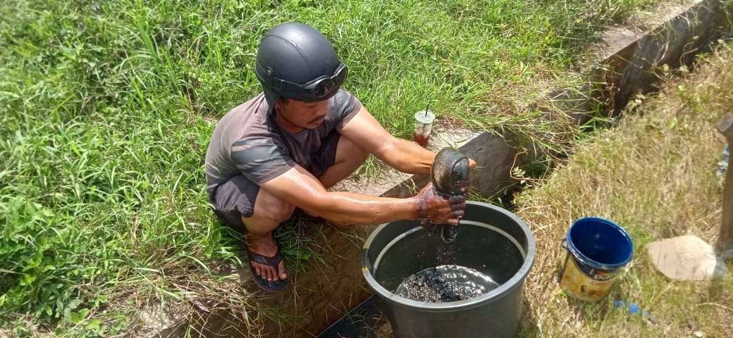 Ari saat memeras minyak ke dalam bak. (Foto: Ahmad Sampurno/Ngopibareng.id)