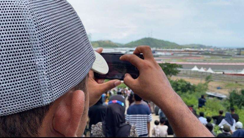 Salah seorang warga ketika mengabadikan momen di Sirkuit Mandalika dari atas bukit. (Foto: Lalu Theo/Ngopibareng.id)