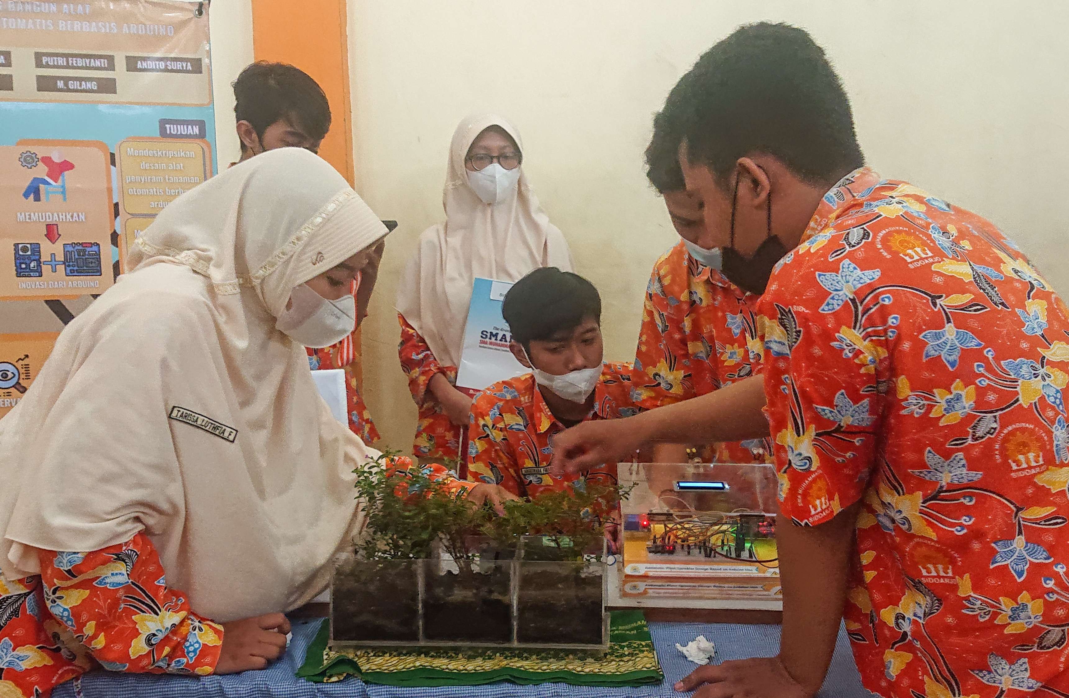 Siswa Smamita sedang menunjukkan cara kerja penyiram tanaman otomatis. (Foto: Aini Arifin/Ngopibareng.id)