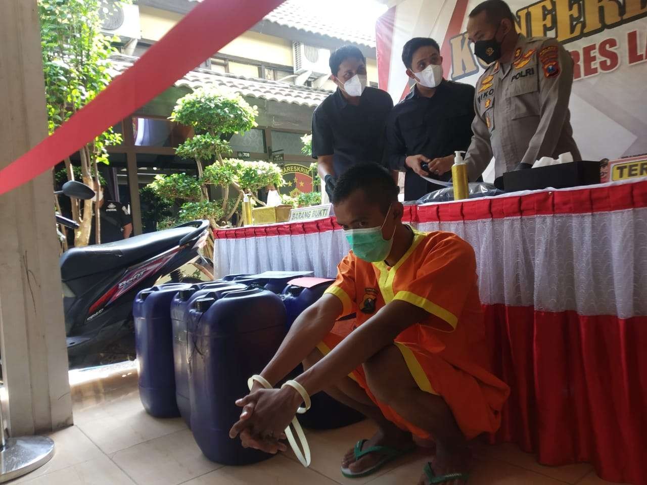 Kapolres Lamongan AKBP Miko Indrayana dan tersangka dengan barang bukti jiriken yang dipakai, minyak goreng oplosan. (Foto: Imron Rosidi/Ngopibareng.id)