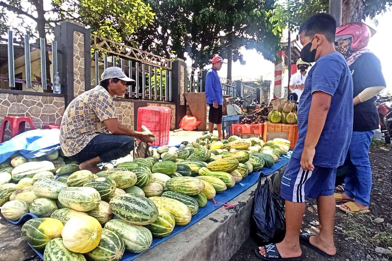 Fahmi sedang melayani  pelangganya yang membeli buah kerai (foto: Muh Hujaini/Ngopibareng)