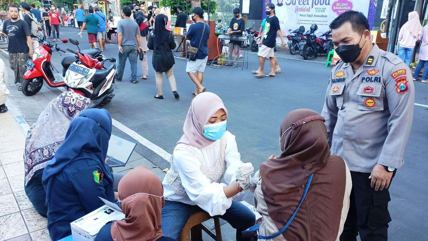 Salah seorang warga melakukan vaksinasi yang digelar Sidokkes Polresta Banyuwangi di area pasar takjil ramadan di Jalan Brigjen Katamso (Foto: Muh Hujaini/Ngopibareng.id)