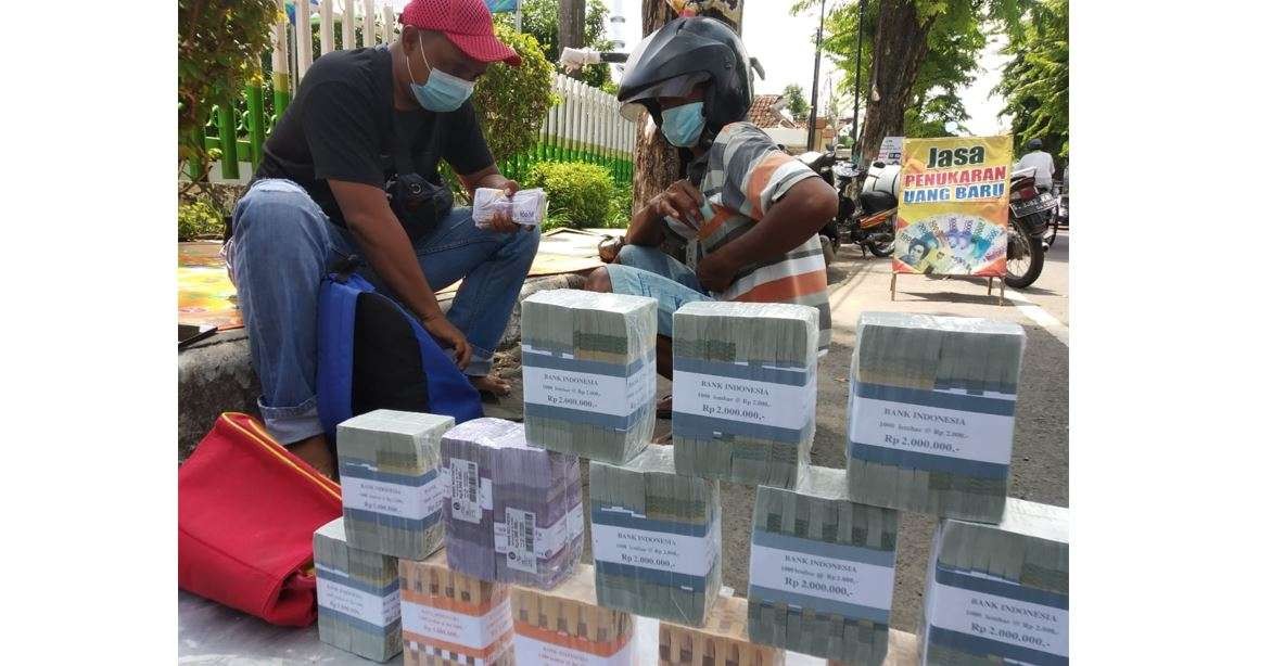 Penjual uang baru di Jalan Basuki Rahmat, Lamongan sedang melayani pembeli. (Foto: Imron Rosidi/Ngopibareng.id)