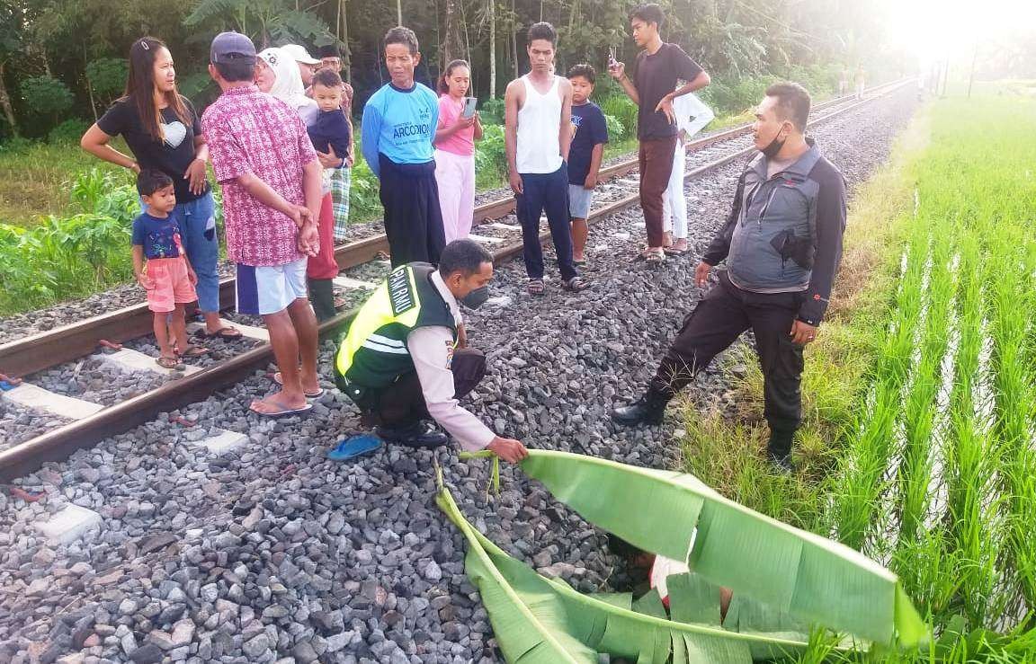 Petugas menutupi jenazah korban yang tertabrak KA Wijaya Kusuma yang melaju dari arah Stasiuan Kali Setail menuju Stasiun Temuguruh tepatnya di wilayah Dusun Krajan Kulon, Desa Temuguruh, Kecamatan Sempu, Banyuwangi, Senin 11 April 2022. (Foto: Istimewa)