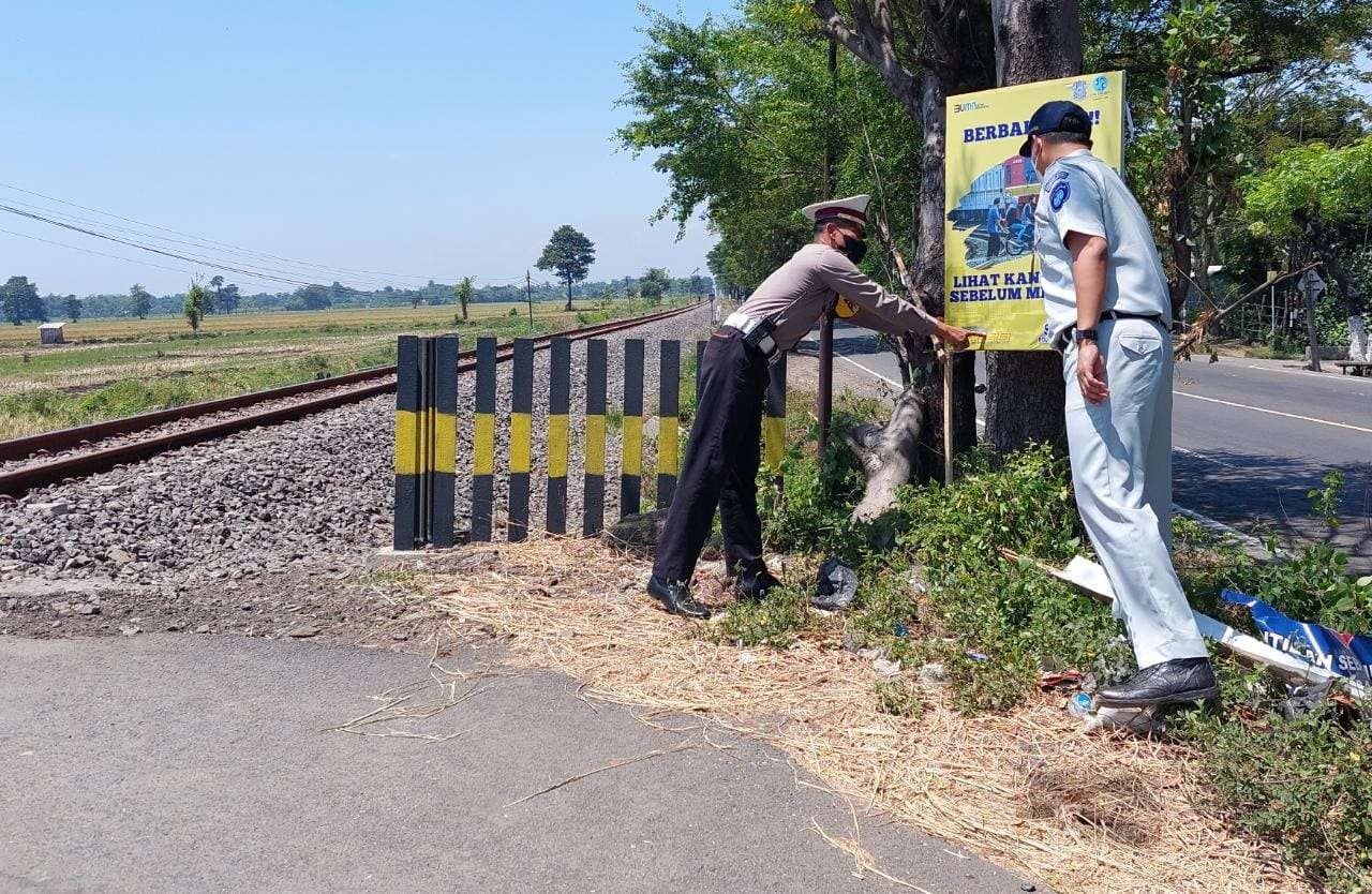 Salah satu perlintasan KA di Probolinggo yang dipasangai banner peringatan agar pengguna jalan waspada. (Foto: Ikhsan Mahmudi/Ngopibareng.id)