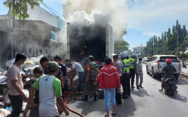 Warga bergotong royong memadamkan api dan menyelamatkan barang paketan dari mobil box yang terbakar.(foto: satlantas Polres Situbondo)