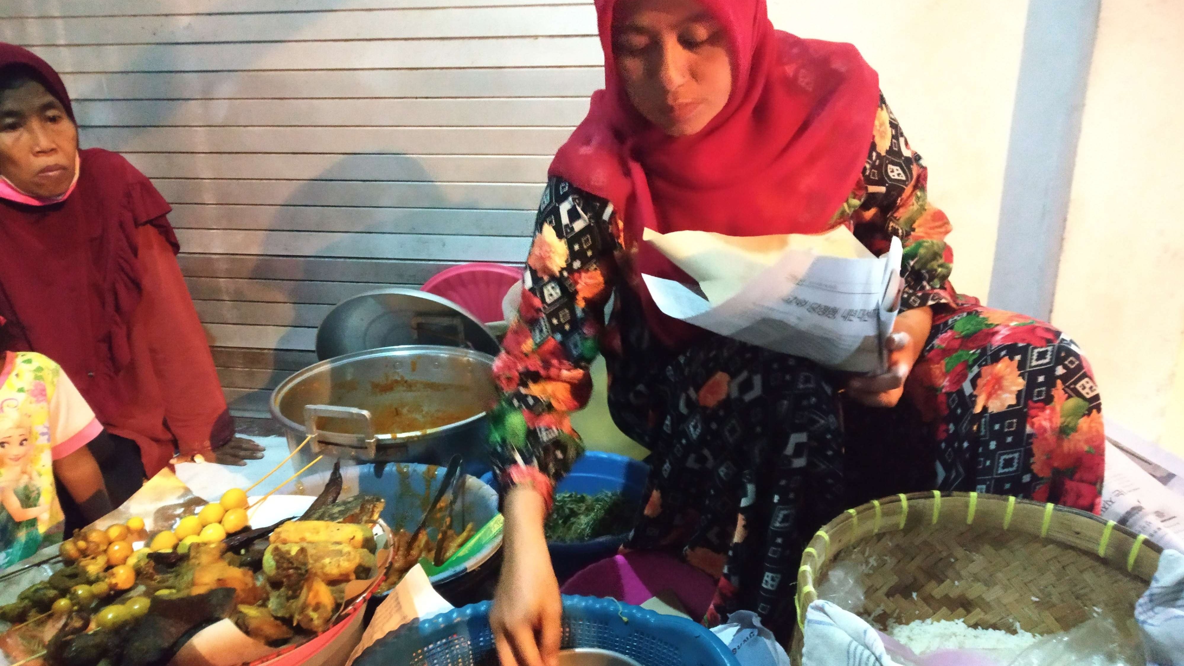 Penjual nasi Boran yang mangkal di sudut kota Lamongan sedang melayani pembeli. (Foto: Imron Rosidi/Ngopibareng.id)