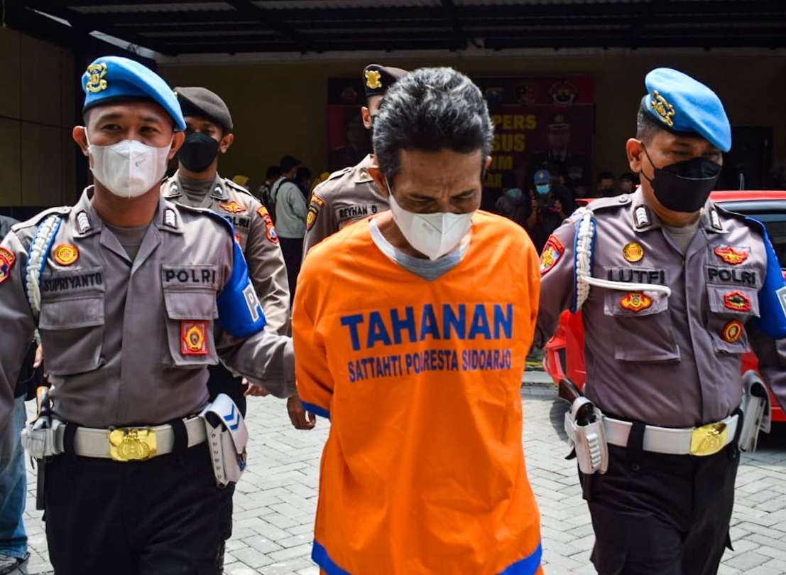 Tersangka H (baju oren) saat diamankan Polresta Sidoarjo (foto:Aini/Ngopibareng.id)