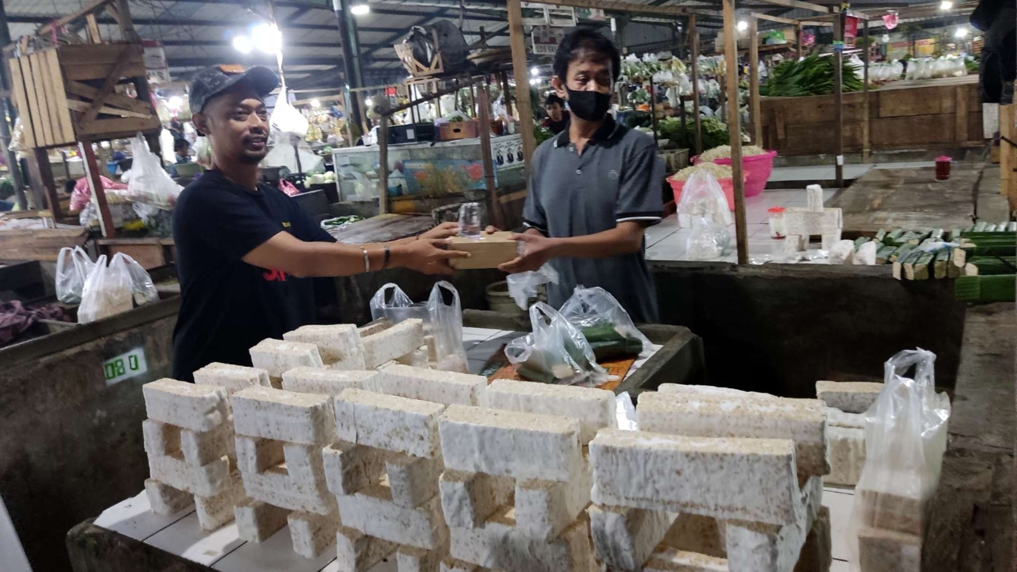 Sekretaris Sahabat Indonesia Satu, Fidi Eka Suwandi (kiri) saat membagikan malan sahur gratis di Pasar Paing, Surabaya, Rabu 20 April 2022 dini hari. (Foto: Fariz Yarbo/Ngopibareng.id)