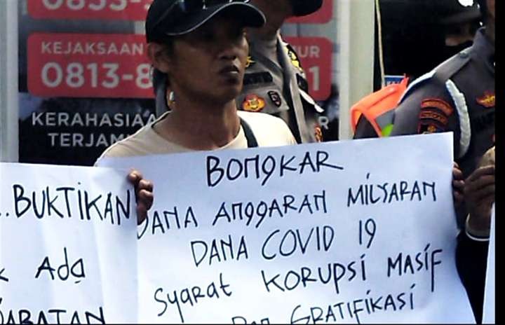 Seorang perwakilan Forum LSM Bondowoso membentangkan poster mendesak Kejari Bondowoso mengusut kasus dugaan korupsi.(Foto: Guido Saphan/ngopibareng.id)