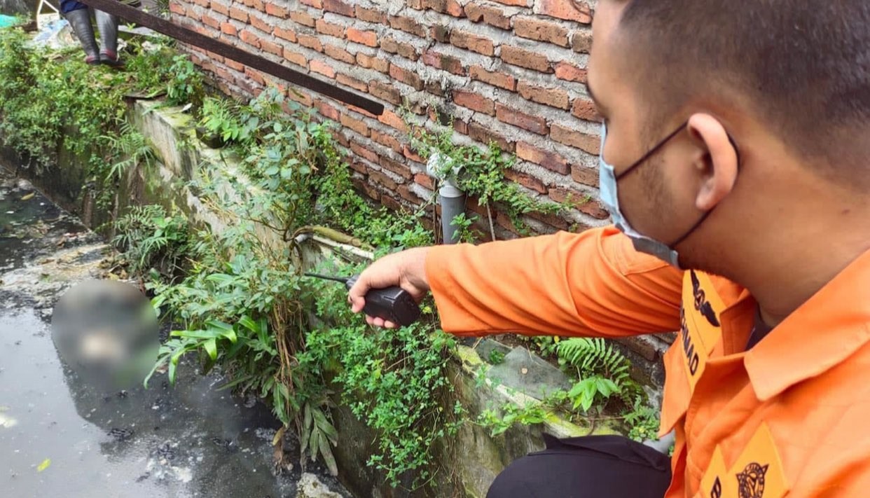 Petugas menunjukkan bayi nahas yang mengambang di sungai Jalan Jemur Ngawinan. Warga Jemur Ngawinan menemukan bayi usia satu hari di sungai belakang rumahnya, Rabu 8 Juni 2022. (Foto: Istimewa)