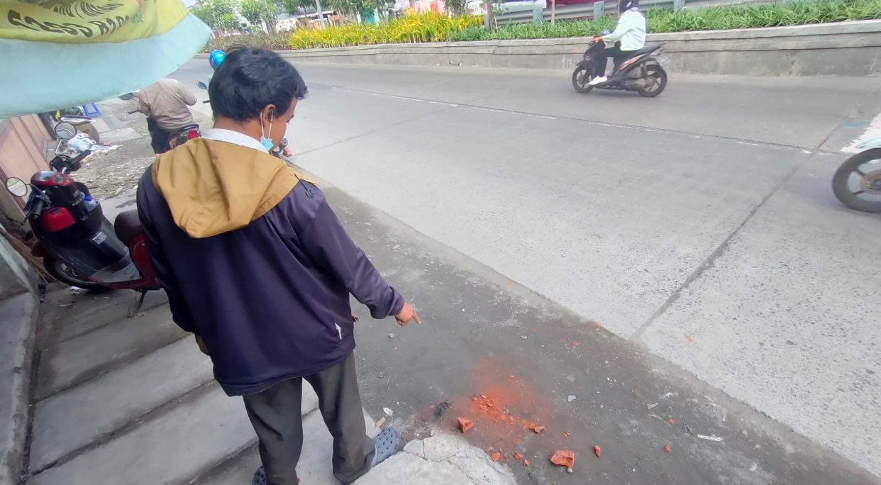 Salah seorang warga menunjukan bekas batu bata untuk pengeroyokan (Foto: istimewa)