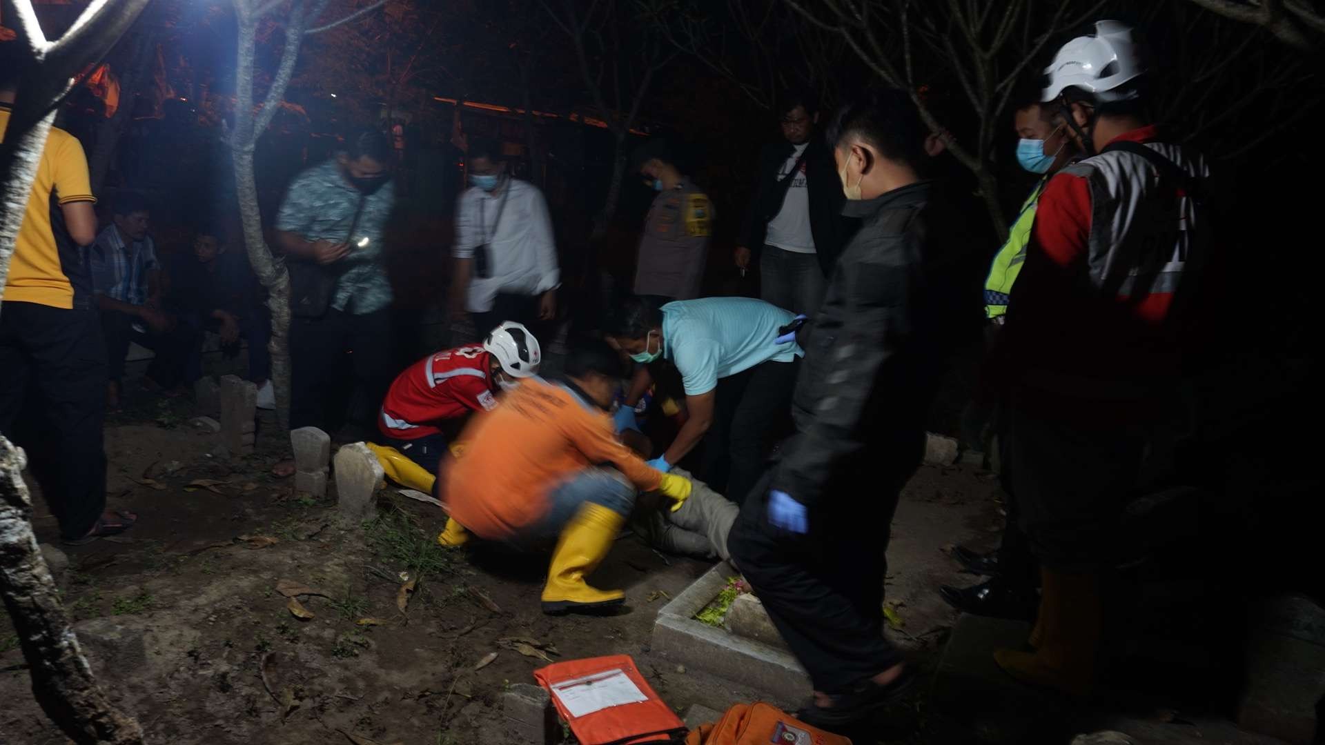 Relawan bersama pihak kepolisian mengevakuasi jasad korban bunuh diri di kuburan istri. (Foto: Deni Lukmantara/Ngopibareng.id)