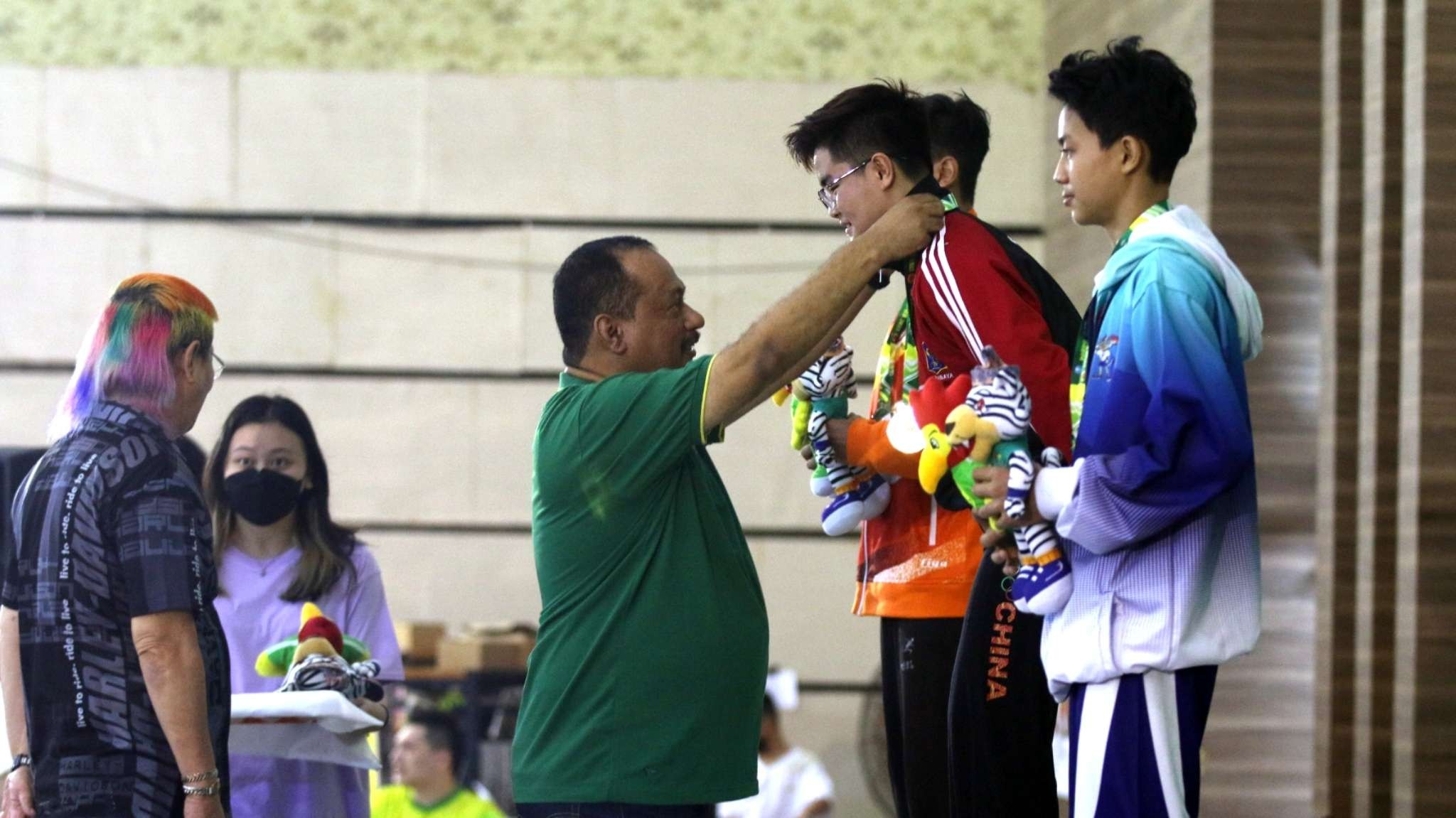 Ketua KONI Jatim, M Nabil saat mengalungkan medali emas kepada Atlet Wushu Surabaya, Jeremiah Mathias Muntu di Gedung Serba Guna Jember, Minggu 26 Juni 2022. (Foto: Fariz Yarbo/Ngopibareng.id)