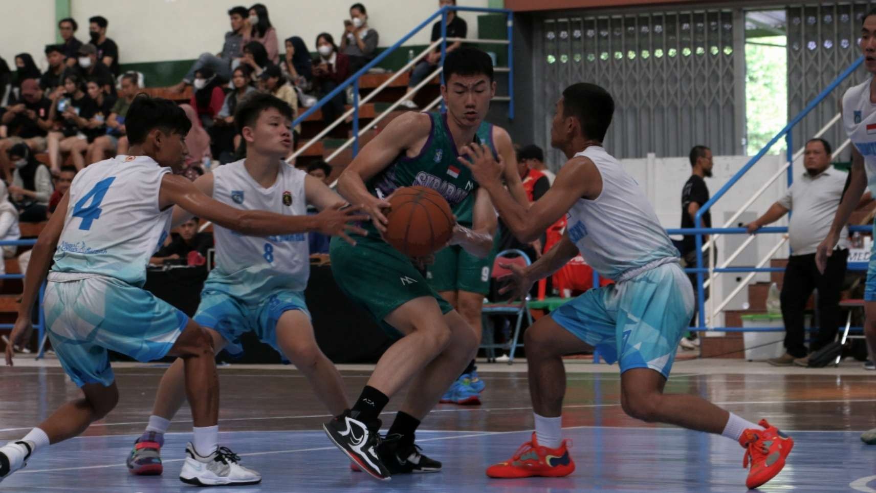 Pemain Surabaya, Cliff Louis (hijau) mencoba menembus pertahanan Ngawi pada babak semifinal Porprov VII Jatim di GOR Garuda, Jember, Selasa 28 Juni 2022. (Foto: Fariz Yarbo/Ngopibareng.id)