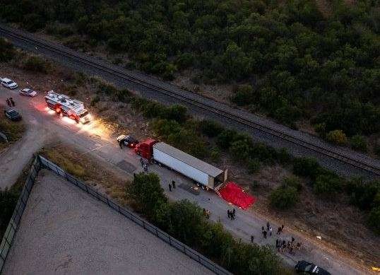 Dalam foto udara, polisi menyelidiki truk trailer berisi jasad migran asal Meksiko di pinggir jalan San Antonio, Texas, Amerika Serikat, Senin 27 Juni 2022. (Foto: Jordan Vonderhaar/ GETTY IMAGES NORTH AMERICA/Getty Images via AFP)