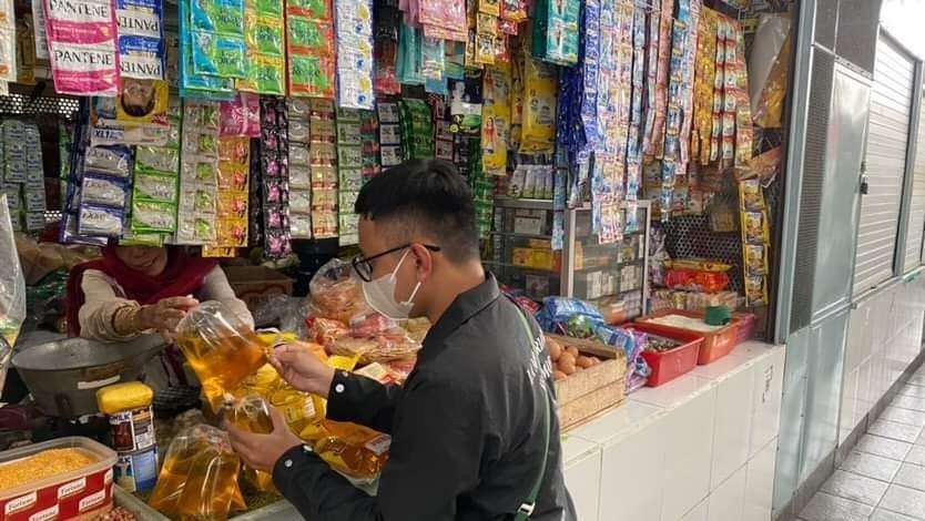 Salah satu pembeli minyak goreng curah di Pasar Kasin, Kota Malang, mengeluhkan ribetnya pakai aplikasi PeduliLindungi. (Foto: Lalu Theo/Ngopibareng.id)