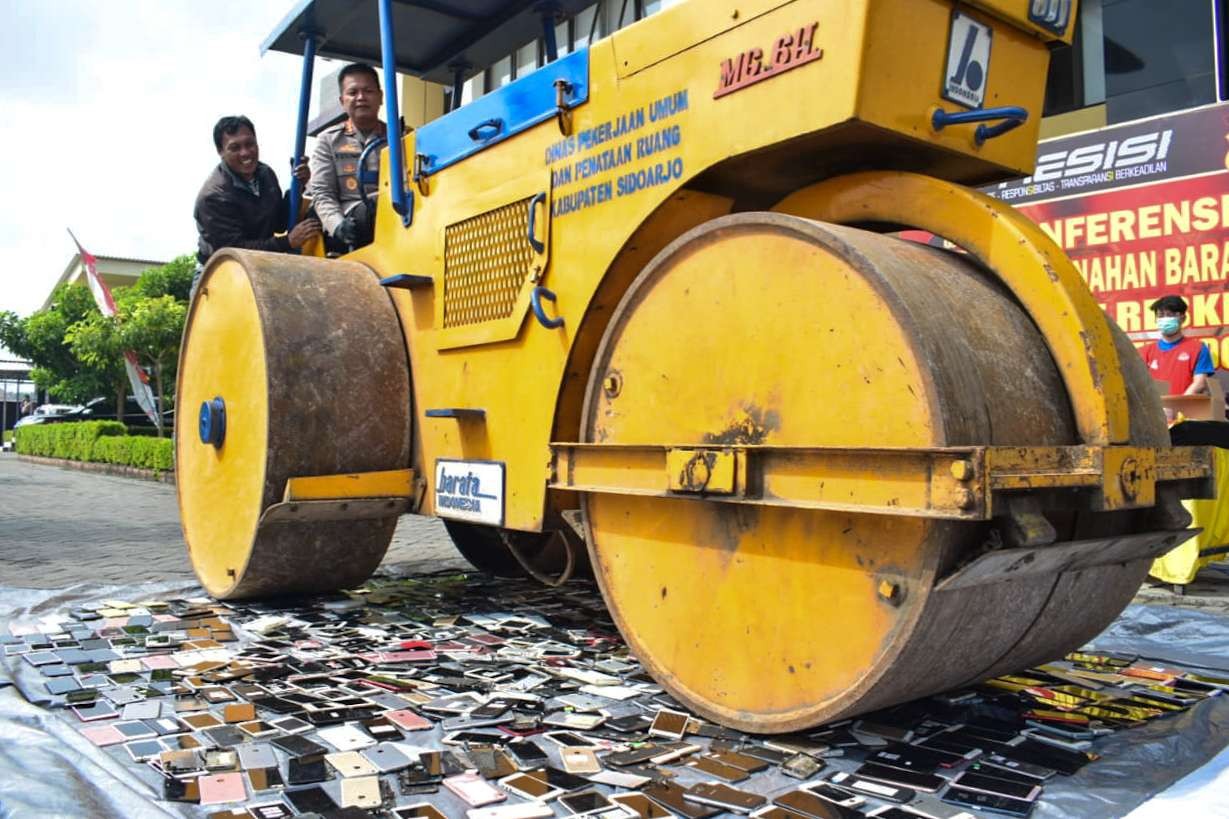 Kapolresta Sidoarjo musnahkan ratusan hp merk Sony dan Iphone menggunakan alat berat (foto : Aini/Ngopibareng.id)