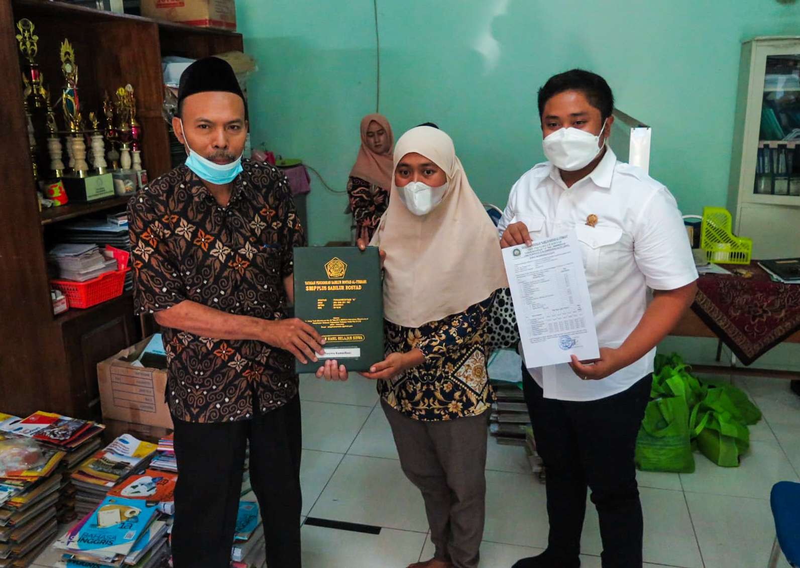 Yati (tengah) ketika mendapatkan ijazah kelulusan anaknya sehingga bisa melanjutkan ke SMA. (Foto: Aini Arifin/Ngopibareng.id)