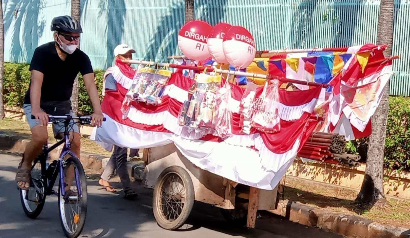 Sejumlah pedagang bendera dan umbul umbul tujuh belasan menjajakan dagangannya dari kampung ke kampung, mereka mengeluh sepinya pembeli ( foto: Asmanu/ngopibareng.id)