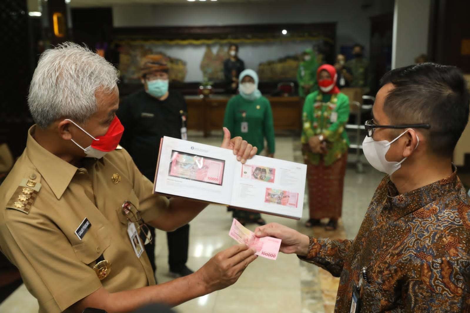 Kepala Perwakilan Bank Indonesia Provinsi Jawa Tengah, Rahmat Dwisaputra menyerahkan buku album berisi tujuh uang kertas dengan desain baru itu mulai pecahan Rp1.000 sampai Rp100.000 kepada Gubernur Jawa Tengah Ganjar Pranowo. (Foto: Humas Pemprov Jatim)