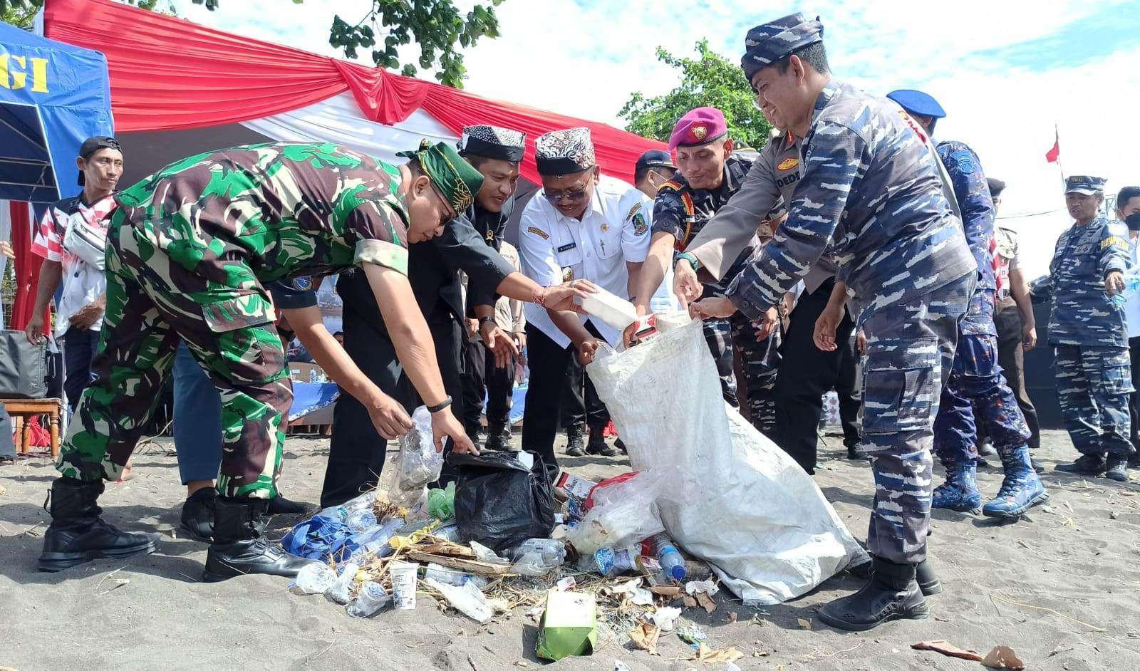 Komandan Lanal Banyuwangi, Letkol Laut (P) Ansori memungut sampah di pantai Sawo Jejer, Kelurahan, Bulusan, Kecamatan Kalipuro, Banyuwangi, Jawa Timur. (Foto: Muh Hujaini/Ngopibareng.id)