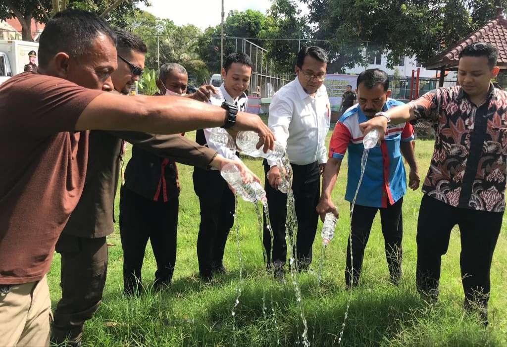 Petugas Kejaksaan Negeri Banyuwangi memusnahkan barang bukti minuman keras ke lubang yang sudah disiapkan. (Foto: Kejari Banyuwangi)