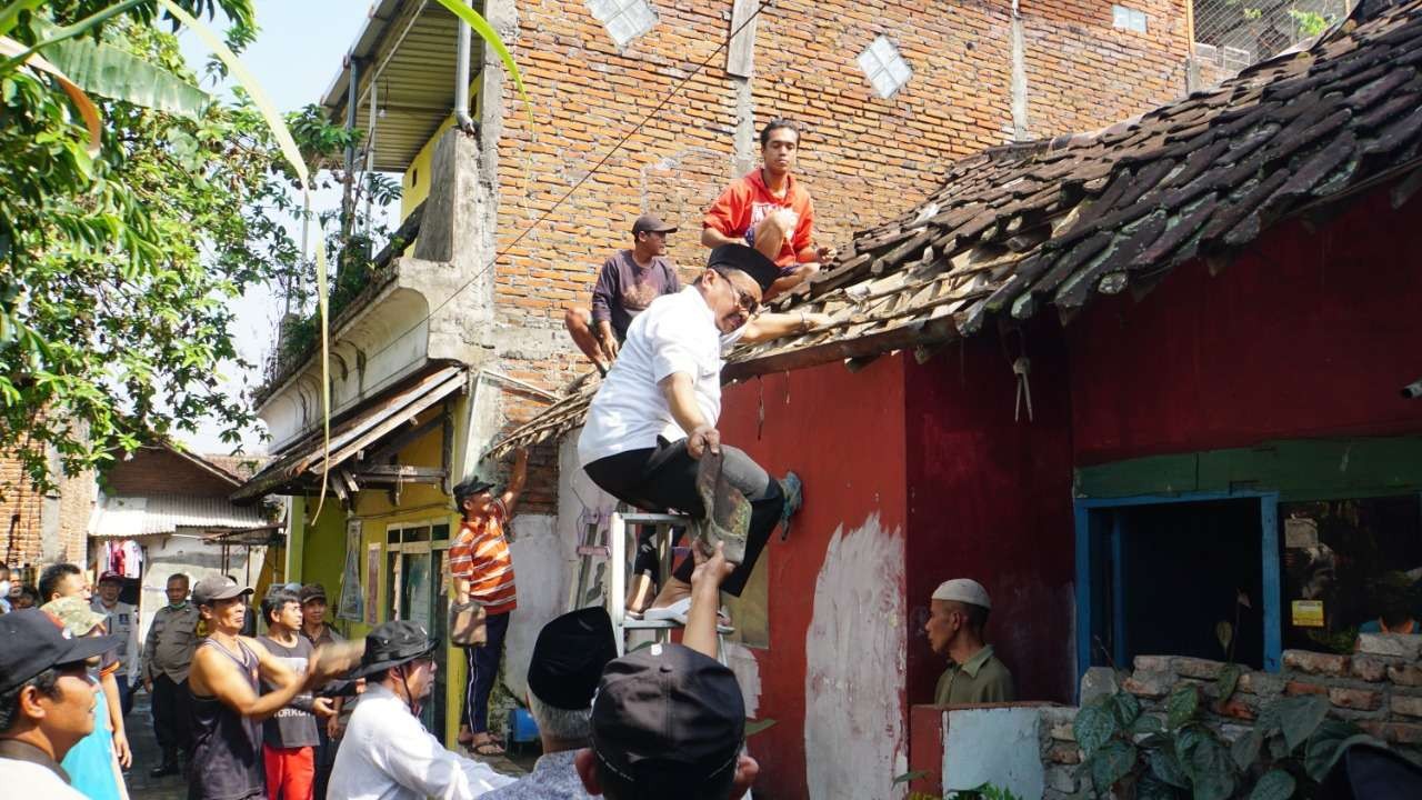 Prof. M. Mas’ud Said Ketua Yayasan Bidang Sosial Sabilillah memasang genting saat bedah rumah. (Foto: LAZIS Sabilillah)