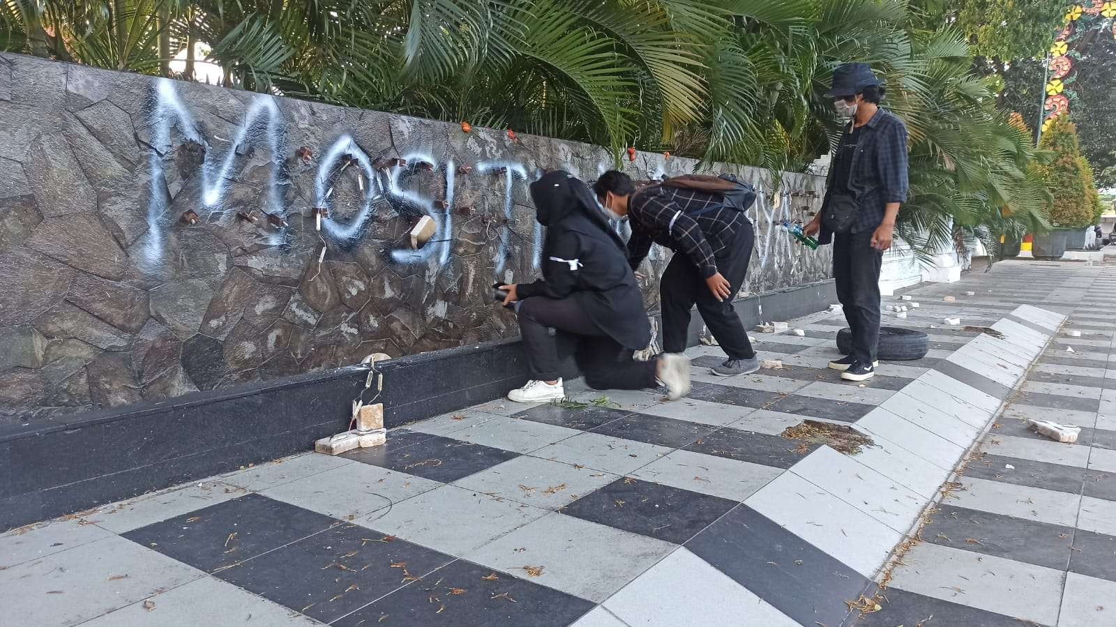 Beberapa peserta aksi menuliskan kalimat mosi tidak percaya di papan nama Kantor Bupati Banyuwangi yang sudah dirusak (Foto: Muh Hujaini/Ngopibareng.id)