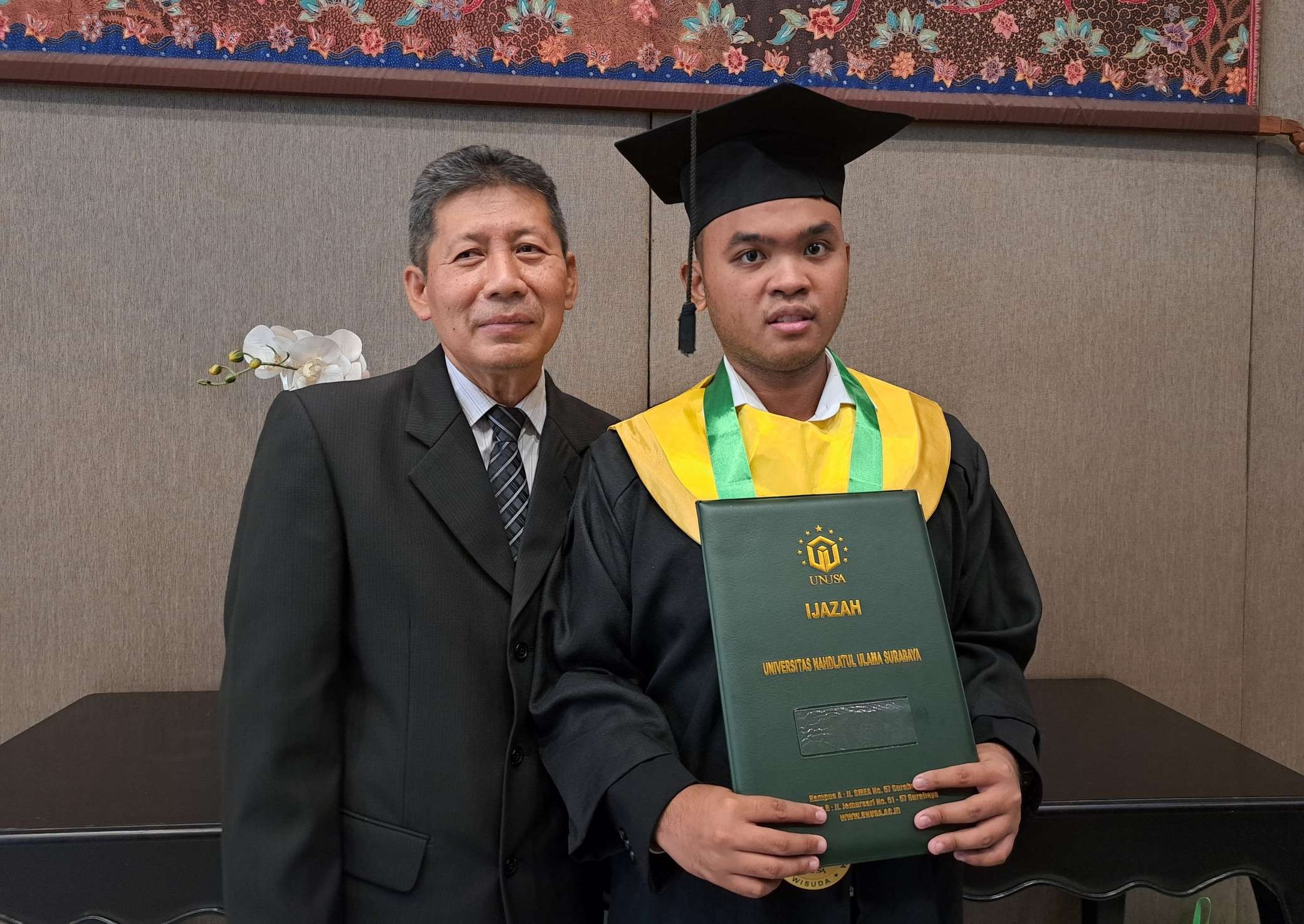 Anharu (kanan) mahasiswa penyandang Autism di Unusa didamping sang ayah, Nawa Gularso usai prosesi wisuda. (Foto: Pita Sari/Ngopibareng.id)