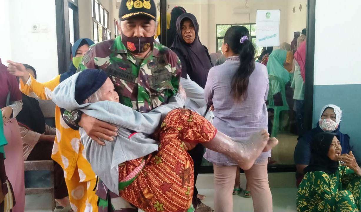 Serma Nurhadi menggendong Nenek Siah untuk menngambil bantuan BLT BBM di Kantor Desa Bangsring. (Foto: Istimewa)