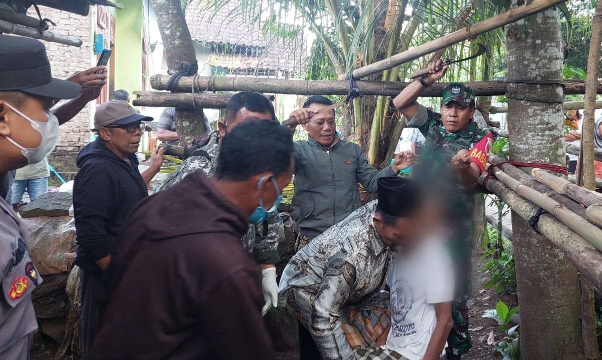 Petugas bersama warga menurunkan korban dari tempatnya gantung diri. (Foto: Dokumentasi warga)