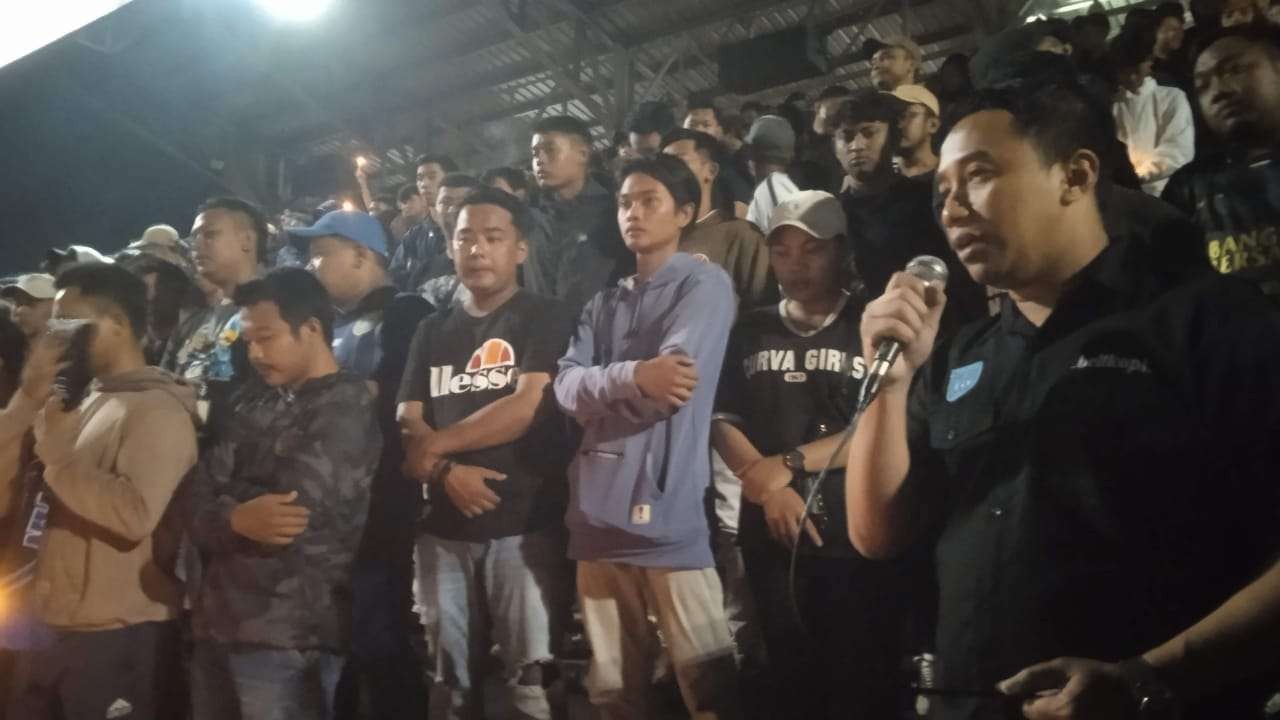 Keterangan Foto : Kelompok suporter Persela Lamongan, LA Mania dan Curva Boys 1967 mengggelar doa bersama tragedi Kanjuruhan di Stadion Surajaya Lamongan (Foto:Imron Rosidi/Ngooibareng.id)