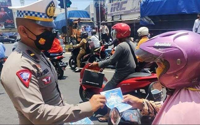 Anggota Satlantas Polres Situbondo membagikan brosur imbauan pentingnya menaati aturan lalu lintas kepada pengendara motor, saat Operasi Zebra Semeru 2022. (Foto: Satlantas Polres Situbondo)