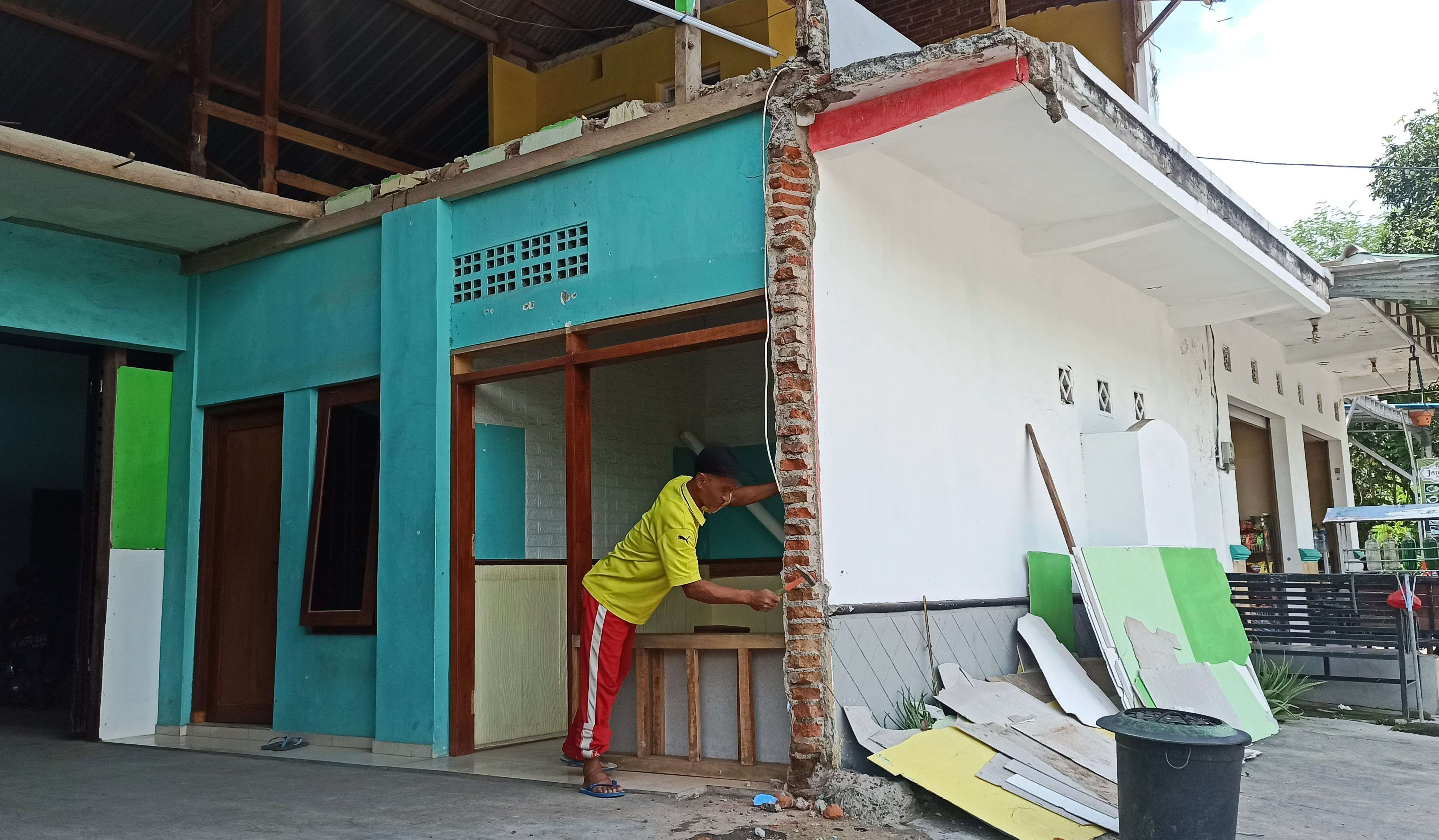 Seorang pekerja muai membongkar bangunan yang terdampak perluasan Stasiun Banyuwangi kota (foto: Muh Hujaini/Ngopibareng.id)