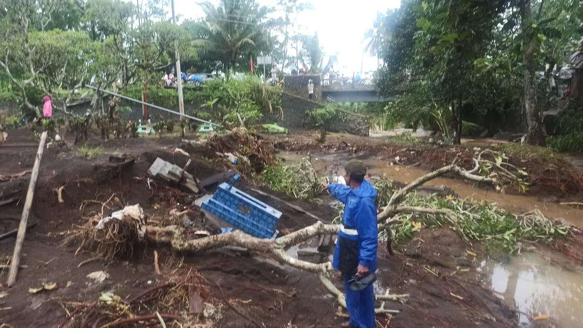 Salam menunjukkan area makam yang tergerus luapan air sungai (Foto: Muh Hujaini/Ngopibareng.id)