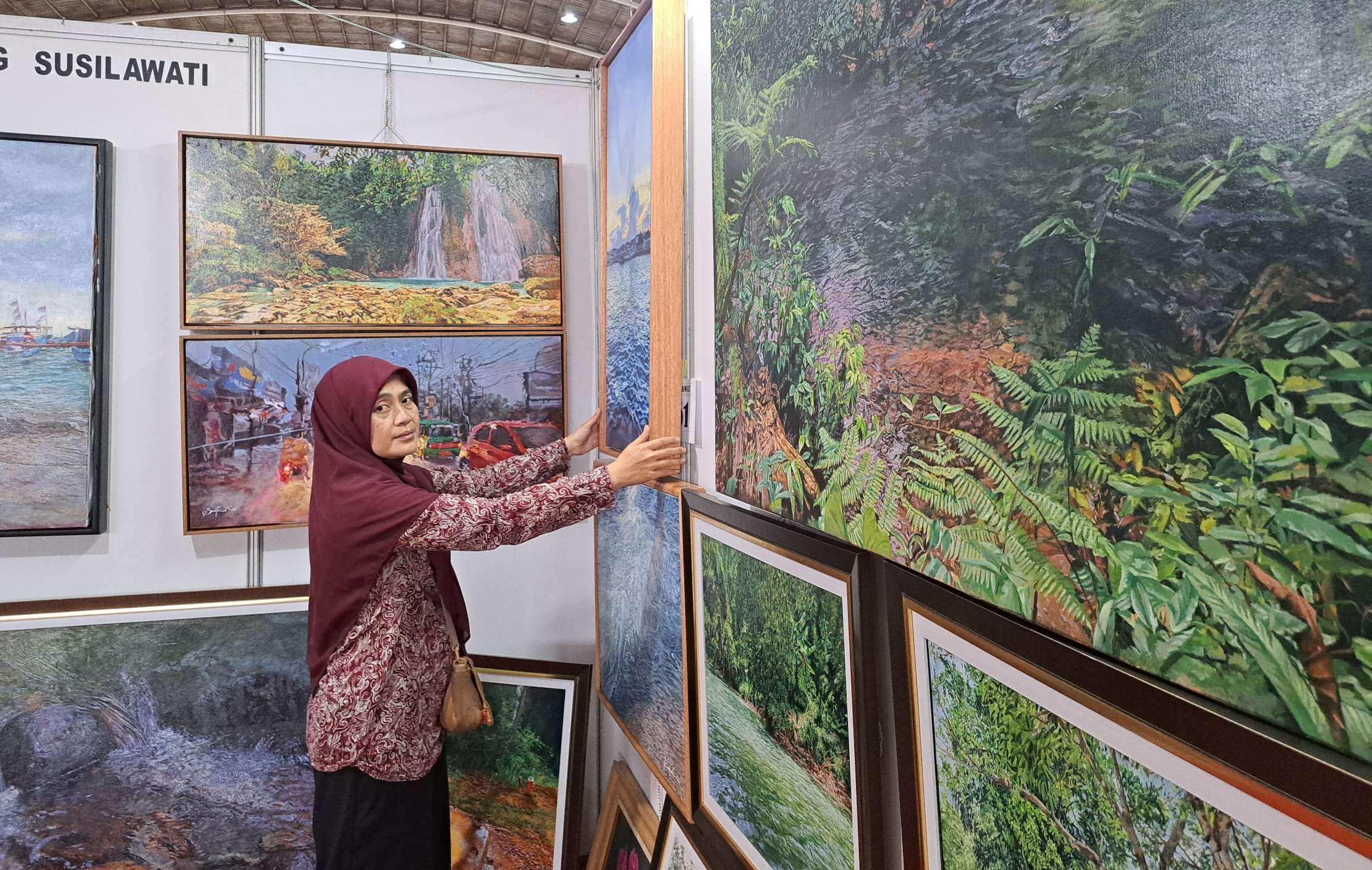 Neng Susilawati, pelukis asal Sukabumi, Jawa Barat, untuk kedua kalinya mengikuti Pasar Seni Lukis Indonesia (PSLI) ke-13 di Jatim Expo, Surabaya. (Foto: Pita Sari/Ngopibareng.id)