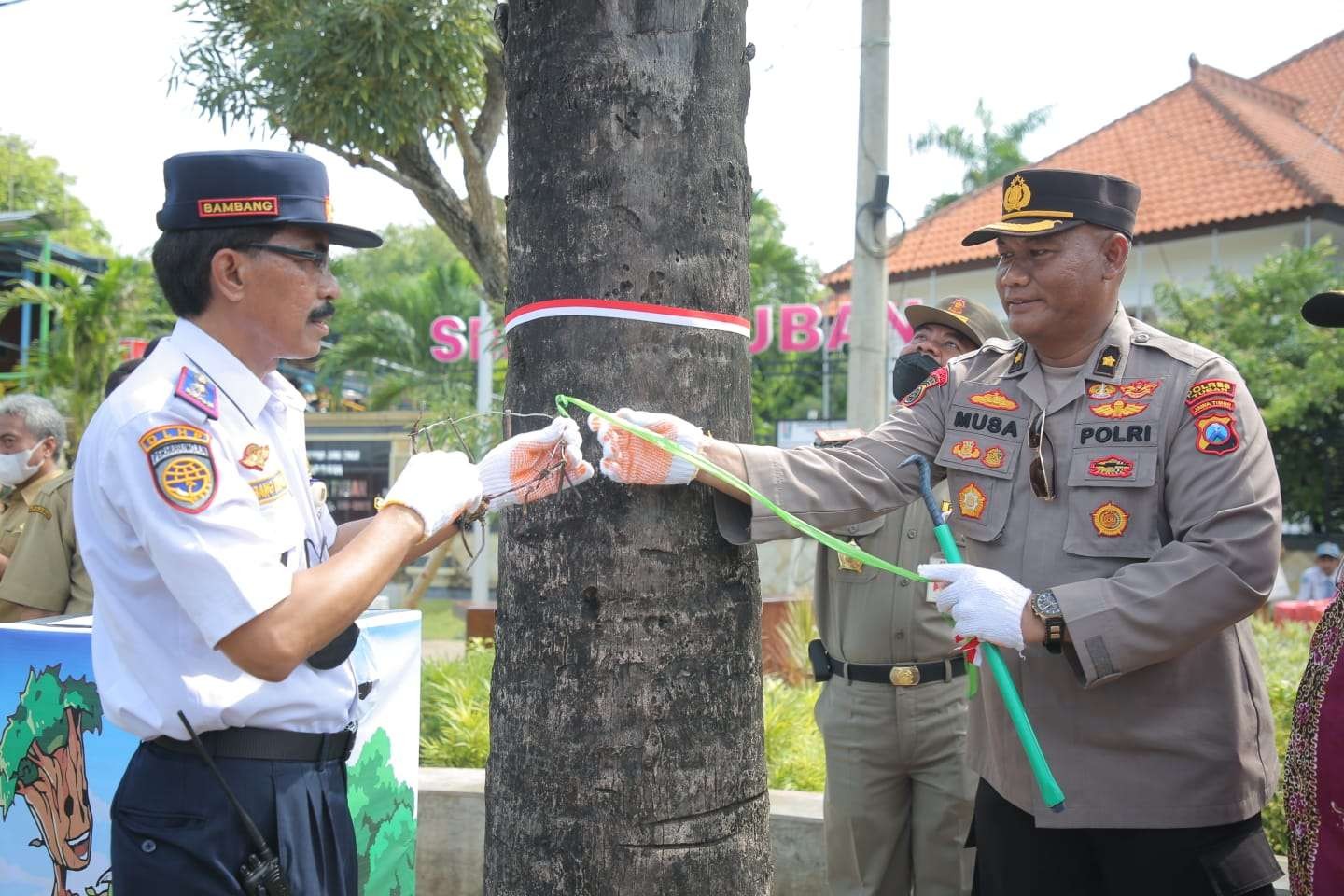 Kepala DLHP Tuban bersama Polres Tuban dan pelajar melakukan aksi cabut paku di pohon. (Foto: Dokumentasi Pemkab Tuban)