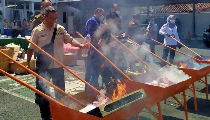 Proses pemusnahan uang palsu dengan cara dibakar di halaman Kantor Kejaksaan Negeri Jember (Foto: Rusdi/Ngopibareng.id)