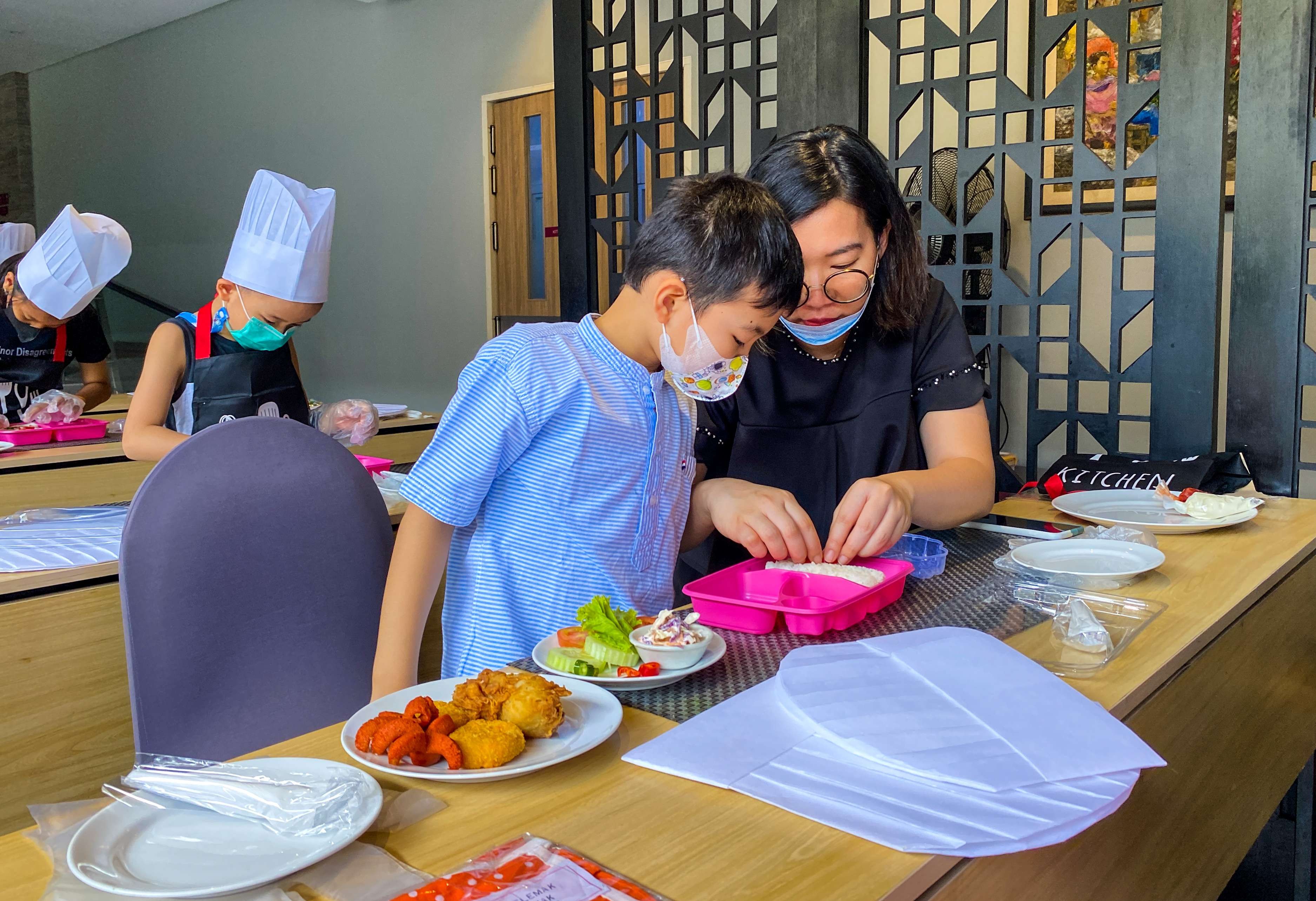 Ibu sedang mengajari anaknya menghias bento box (foto : Aini/Ngopibareng.id)