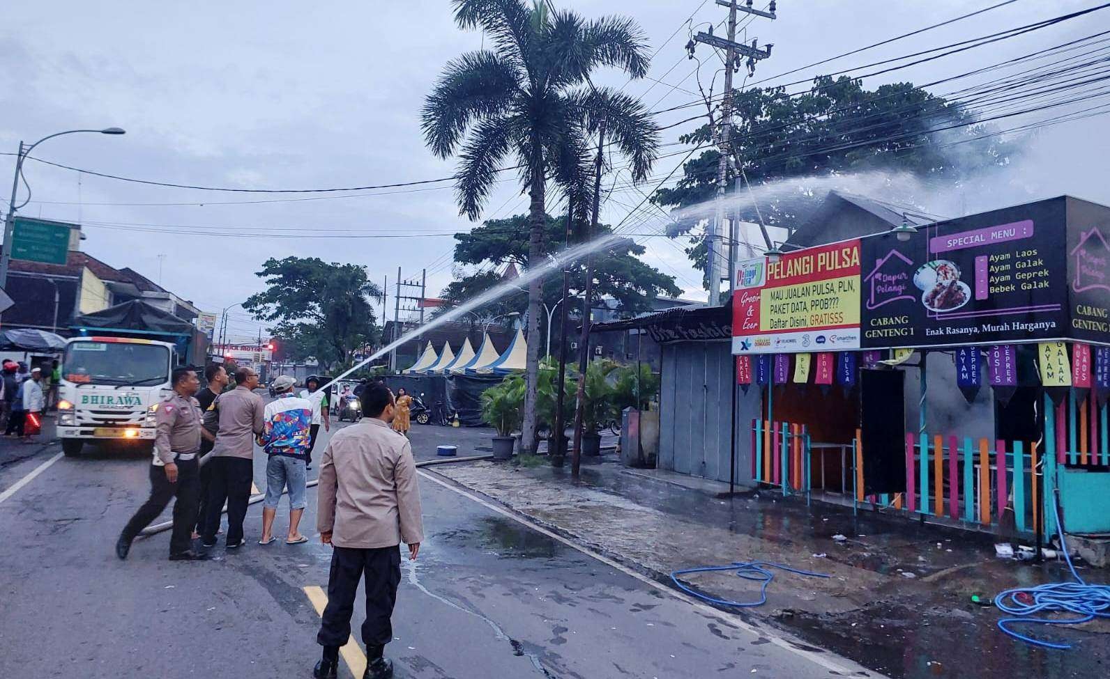 Petugas berupaya memadamkan api di kios pulsa yang ada di Genteng, Banyuwangi, Jawa Timur. (Foto: Istimewa)