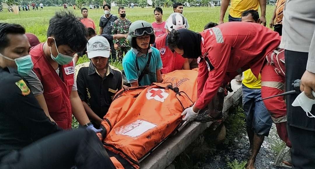 Relawan dibantu warga evakuasi jasad korban dari tengah persawahan.(Foto Deni Lukmantara/Ngopibareng.id)