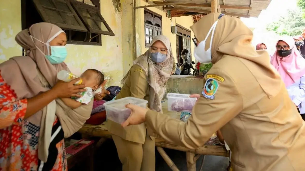 Bupati Banyuwangi Ipuk Fiestiandani menyerahkan bahan pangan kepada seorang ibu untuk peningkatan gizi anak, sehingga cegah kasus stunting. (Foto: Humas Pemkab Banyuwangi)