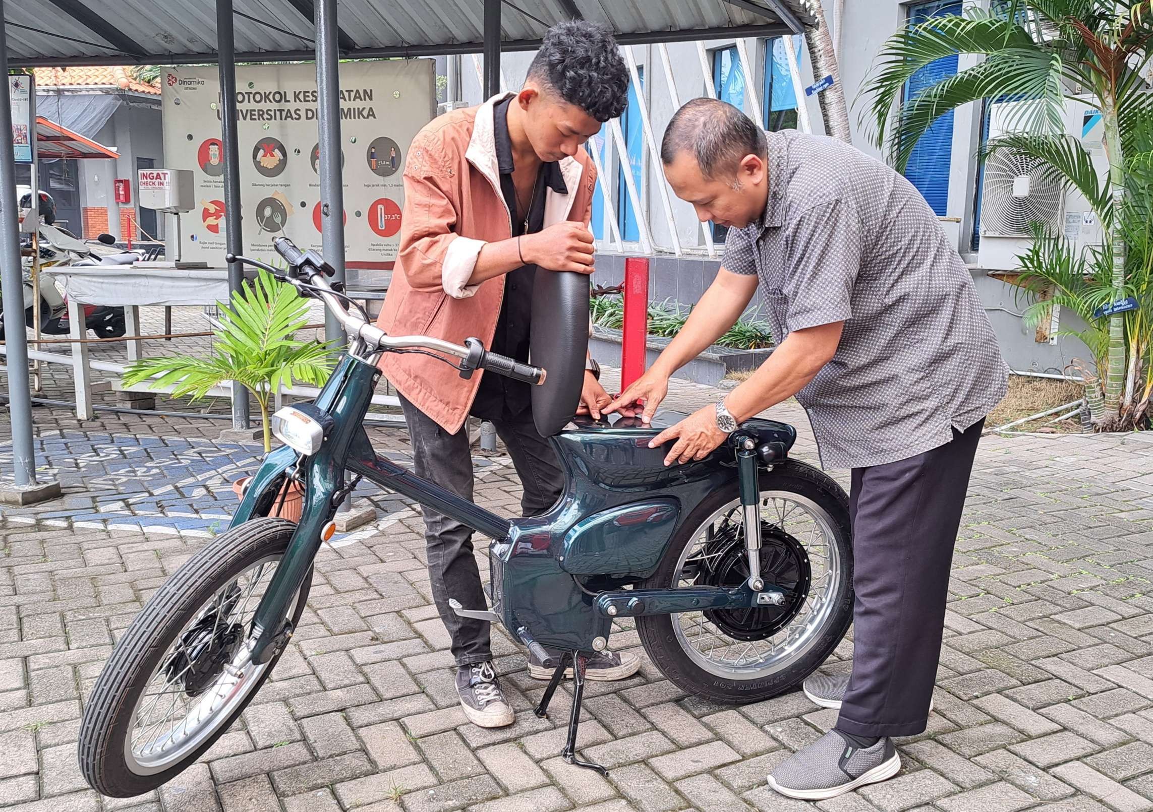 Fadhil Deivan Rashendriya bersama dengan dosenya saat menunjukan motor listrik, inovasinya. (Foto: Pita Sari/Ngopibareng.id)