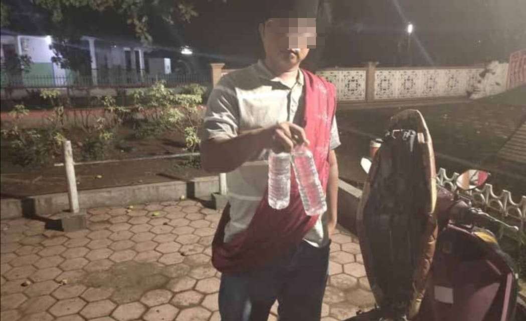 Buruh tani di Situbondo ditangkap anggota Polsek Panji, karena menjual miras jenis arak di kemasan botol air mineral. (Foto: Guido Saphan/Ngopibareng.id)