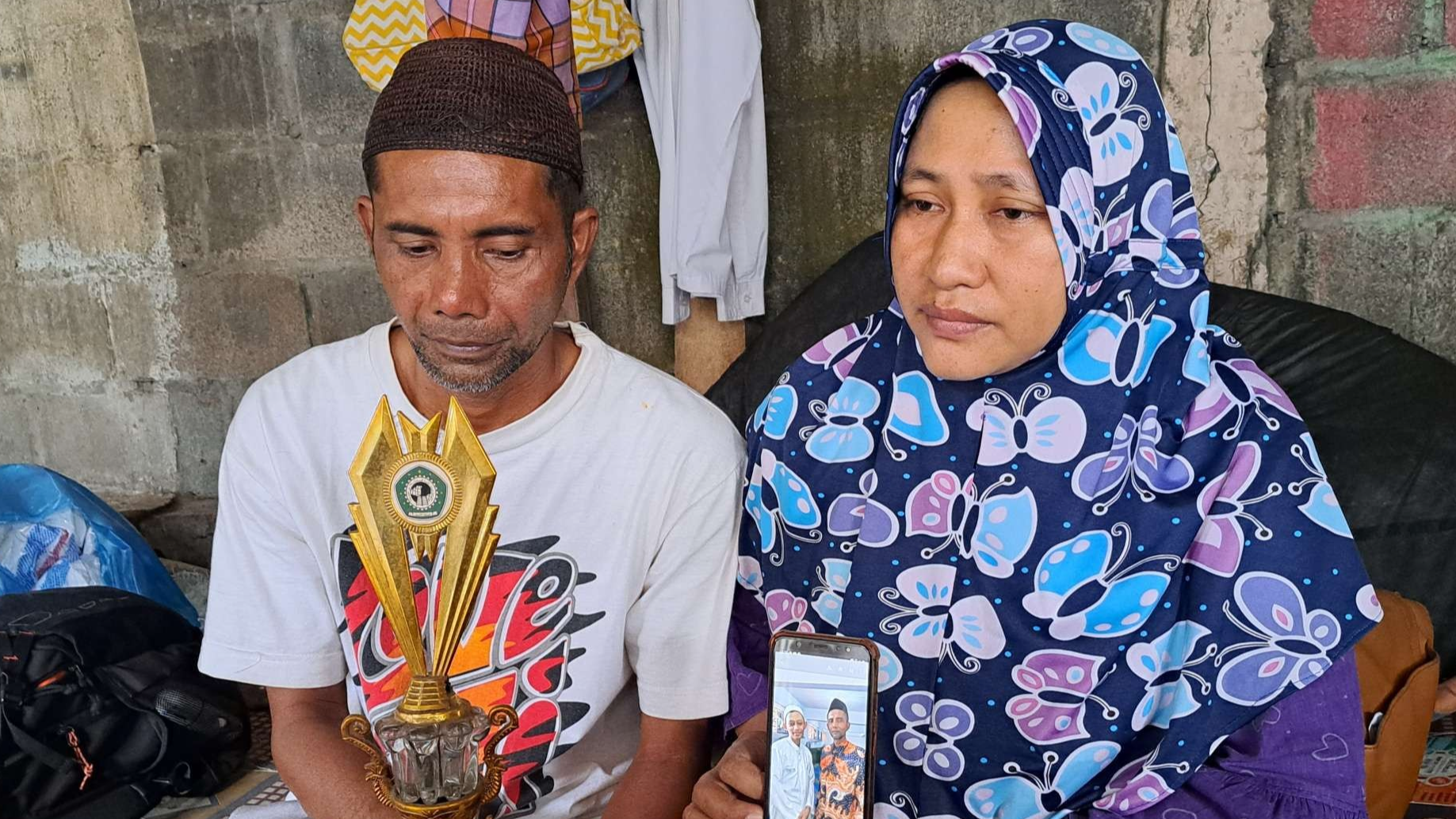 Orang tua Fandi, Ahmad Mustalini dan istrinya, Cholifatur Rosidah, memperlihatkan foto Fandi yang sedang mondok dan piala penghargaanya dalam olimpiade. (Foto: Pita Sari/Ngopibareng.id)