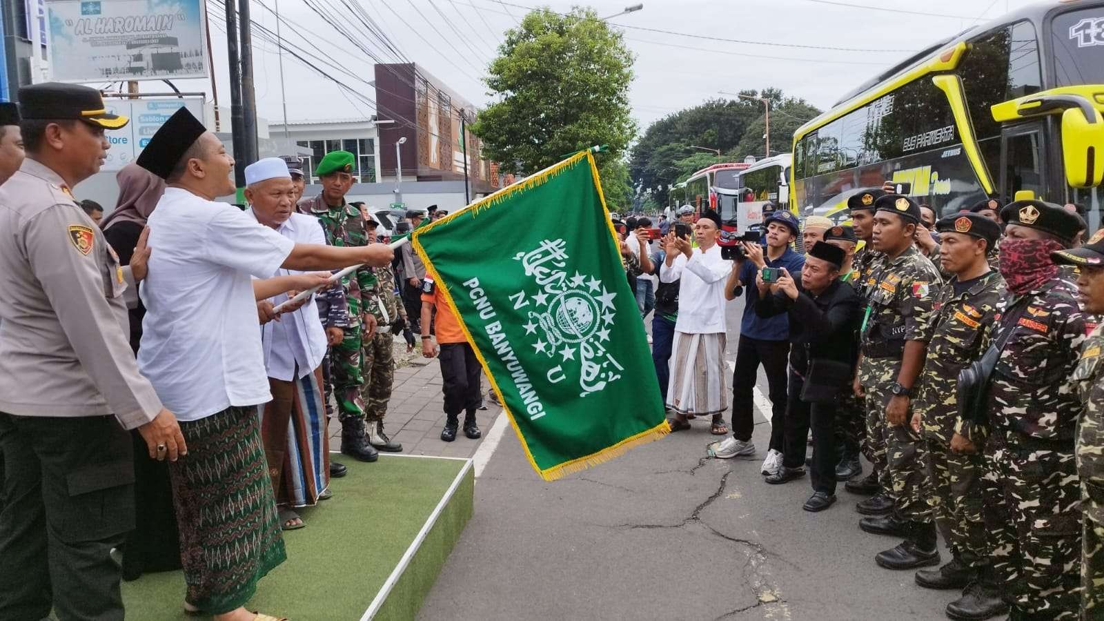 Ketua PCNU Banyuwangi, KH Ali Makki Zaini bersama Bupati Banyuwangi Ipuk Fiestiandani melepas rombongan warga Nahdliyin berangkat ke Sidoarjo. (Foto: Muh Hujaini/Ngopibareng.id)